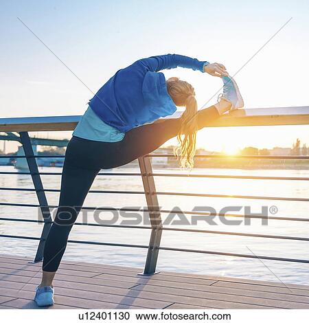 Stock Image - Woman stretching on bridge. Fotosearch