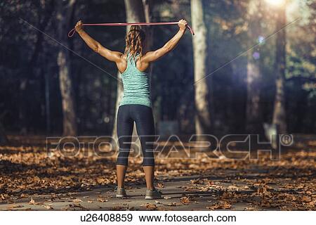 Stock Photo - Woman stretching with elastic band outdoors. Fotosearch