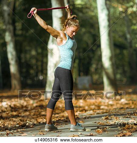 Stock Photograph - Woman stretching with elastic band outdoors. Fotosearch