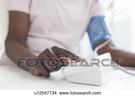 Picture - Woman testing blood pressure. Fotosearch
