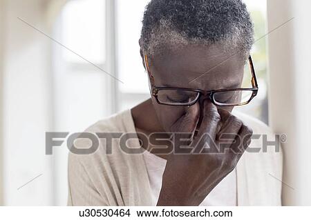 Picture - Woman touching bridge of nose. Fotosearch
