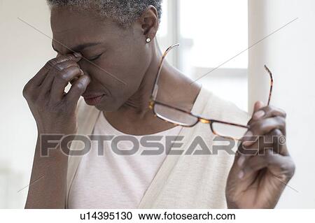 Stock Image - Woman touching bridge of nose. Fotosearch