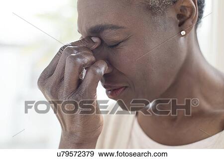 Stock Photo - Woman touching bridge of nose. Fotosearch