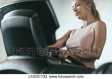 Stock Image - Woman using a treadmill. Fotosearch