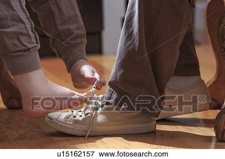 Stock Photo - Woman with TAR Syndrome tying shoelaces with her feet. Fotosearch
