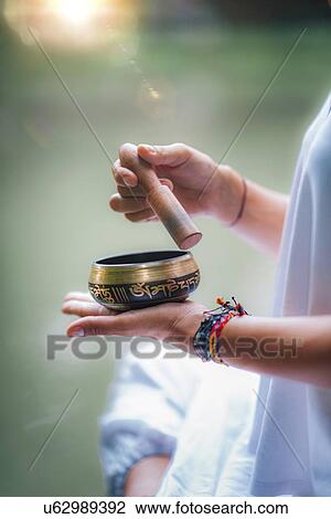 Stock Image - Woman with Tibetan singing bowl. Fotosearch