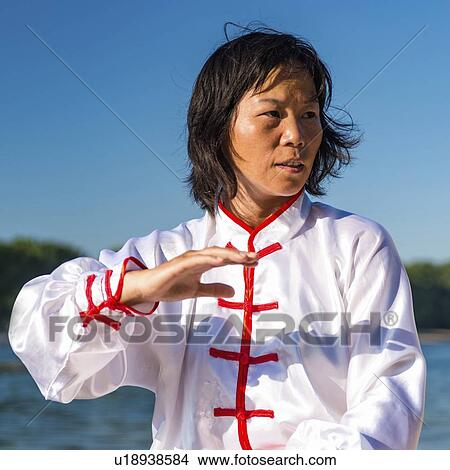 Picture - Women practicing tai chi by lake. Fotosearch