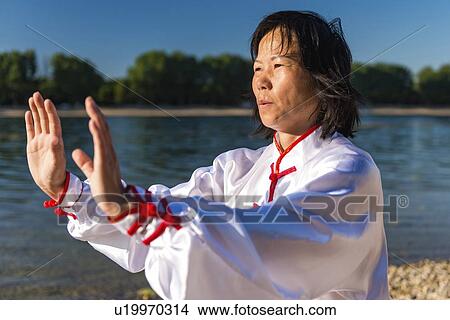 Picture - Women practicing tai chi by lake. Fotosearch