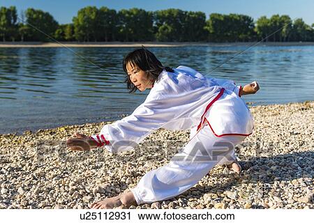 Stock Image - Women practicing tai chi by lake. Fotosearch
