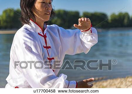 Stock Photo - Women practicing tai chi by lake. Fotosearch