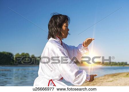 Stock Photo - Women practicing tai chi by lake. Fotosearch