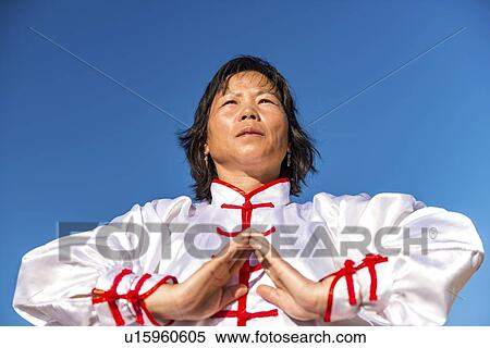 Stock Photography - Women practicing tai chi by lake. Fotosearch