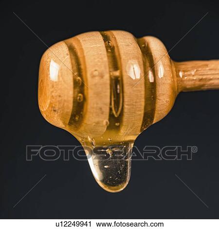 Stock Image - Wooden dipper with flowing honey. Fotosearch