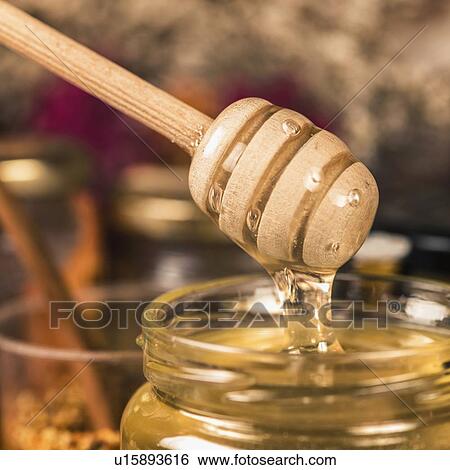 Stock Photograph - Wooden dipper with flowing honey. Fotosearch