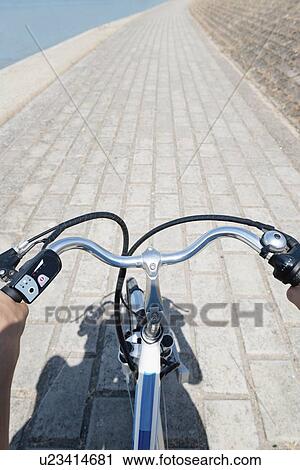 Stock Image - Young woman riding electric bicycle. Fotosearch
