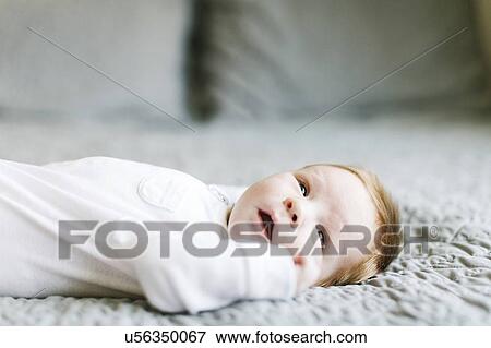 Stock Photo - Baby boy lying on bed. Fotosearch