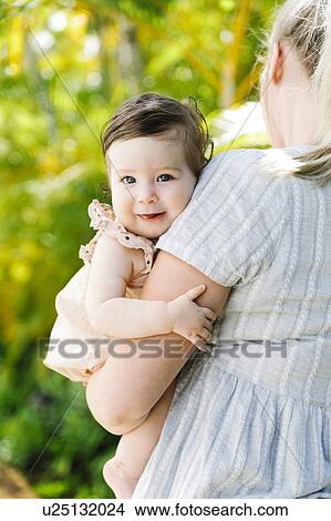 Picture - Baby girl being held by her mother. Fotosearch