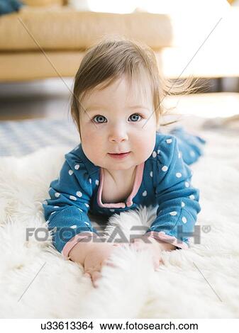 Picture - Baby girl lying on rug. Fotosearch