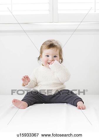 Baby girl sitting under window View Large Photo Image Stock Photo - Baby girl sitting under window. Fotosearch
