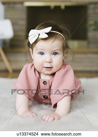 Baby girl wearing bow hair band lying on rug View Large Photo Image Picture - Baby girl wearing bow hair band lying on rug. Fotosearch