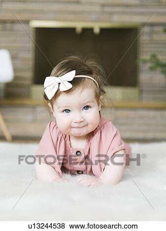 Baby girl wearing bow hair band lying on rug View Large Photo Image Stock Photo - Baby girl wearing bow hair band lying on rug. Fotosearch