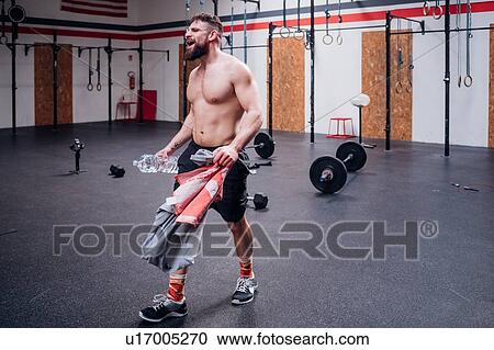 Bare chested young man training, holding bottled water and towel in gym, full length View Large Photo Image Stock Image - Bare chested young man training, holding bottled water and towel in gym, full length. Fotosearch