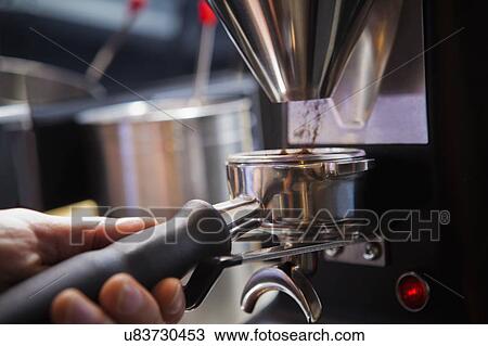 Stock Image - Barista collecting ground coffee in portafilter. Fotosearch