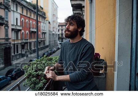 Picture - Bearded young man in deep thought on balcony. Fotosearch