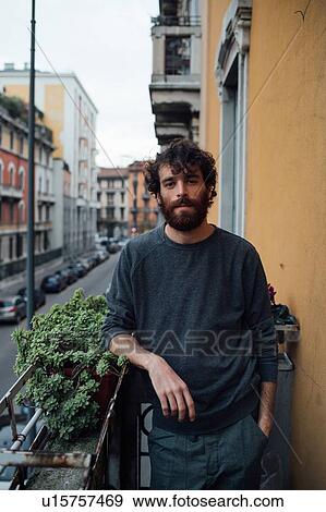 Stock Photo - Bearded young man in deep thought on balcony. Fotosearch