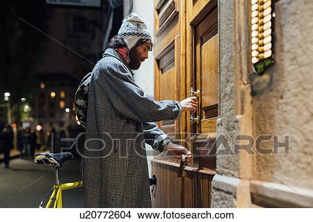 Bearded young man opening door into apartment building View Large Photo Image Picture - Bearded young man opening door into apartment building. Fotosearch