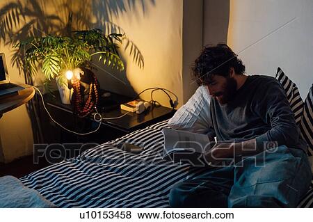 Bearded young man reading book in bed View Large Photo Image Stock Photo - Bearded young man reading book in bed. Fotosearch
