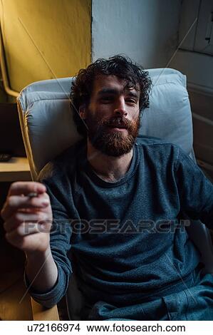 Picture - Bearded young man smoking at home. Fotosearch