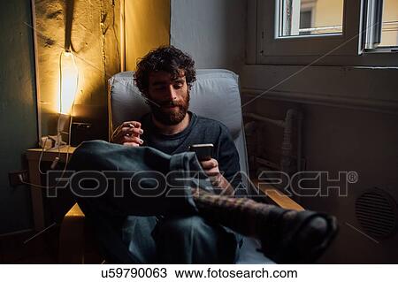 Bearded young man smoking, using smartphone at home View Large Photo Image Stock Image - Bearded young man smoking, using smartphone at home. Fotosearch