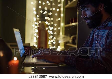 Stock Photo - Bearded young man using laptop at home. Fotosearch