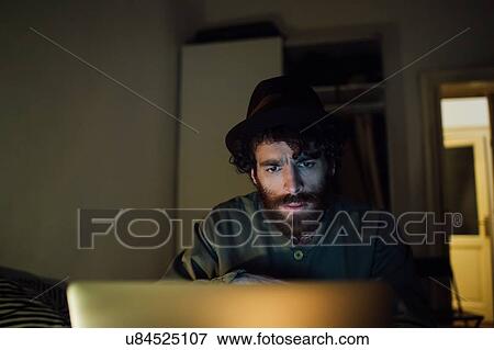 Stock Photo - Bearded young man using laptop at home. Fotosearch