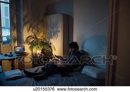Bearded young man using smartphone and laptop in bed View Large Photo Image Stock Photograph - Bearded young man using smartphone and laptop in bed. Fotosearch