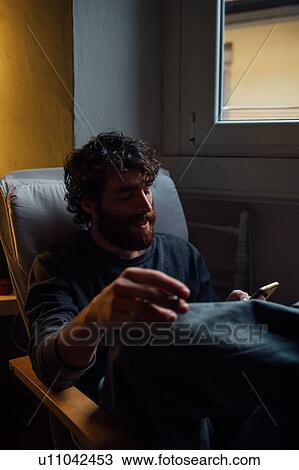 Bearded young man using smartphone at home View Large Photo Image Stock Image - Bearded young man using smartphone at home. Fotosearch