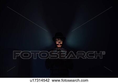Stock Image - Bearded young man using smartphone in dark room. Fotosearch