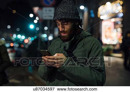 Bearded young man using smartphone on street View Large Photo Image Stock Photo - Bearded young man using smartphone on street. Fotosearch