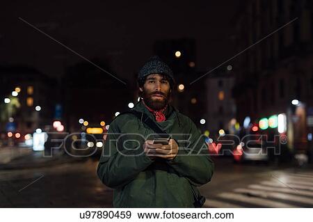 Stock Photo - Bearded young man using smartphone on street. Fotosearch