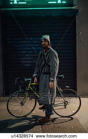 Picture - Bearded young man with bicycle on pavement. Fotosearch