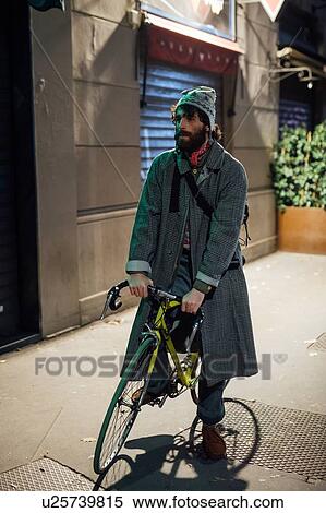 Stock Photography - Bearded young man with bicycle on pavement. Fotosearch