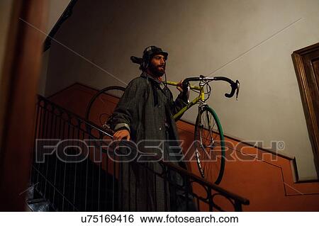 Stock Photograph - Bearded young man with bicycle over shoulder going down stairway. Fotosearch