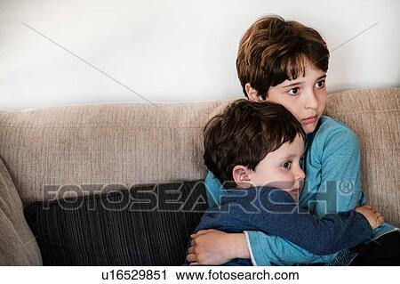 Big brother hugging toddler, staring in disbelief on sofa View Large Photo Image Stock Image - Big brother hugging toddler, staring in disbelief on sofa. Fotosearch