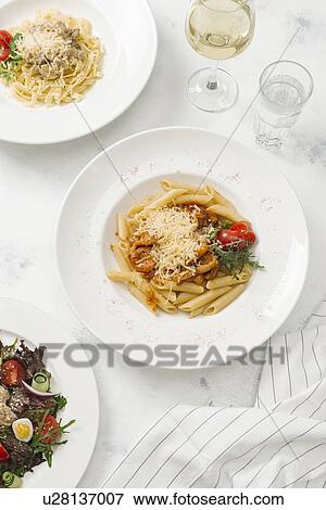 Stock Photo - Bowl of pasta topped with cheese by white wine. Fotosearch