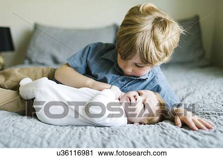Stock Image - Boy and his baby brother on bed. Fotosearch