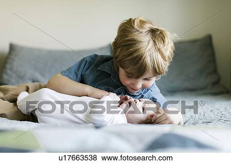 Stock Photo - Boy and his baby brother on bed. Fotosearch