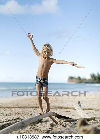 Boy balancing on driftwood View Large Photo Image Stock Photo - Boy balancing on driftwood. Fotosearch