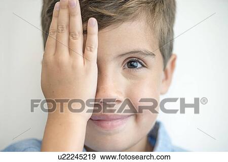 Stock Photo - Boy covering one eye with hand.. Fotosearch