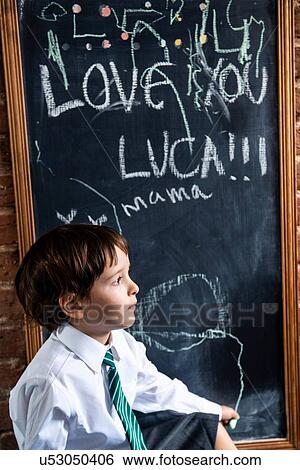 Stock Photograph - Boy in school uniform beside blackboard at home. Fotosearch
